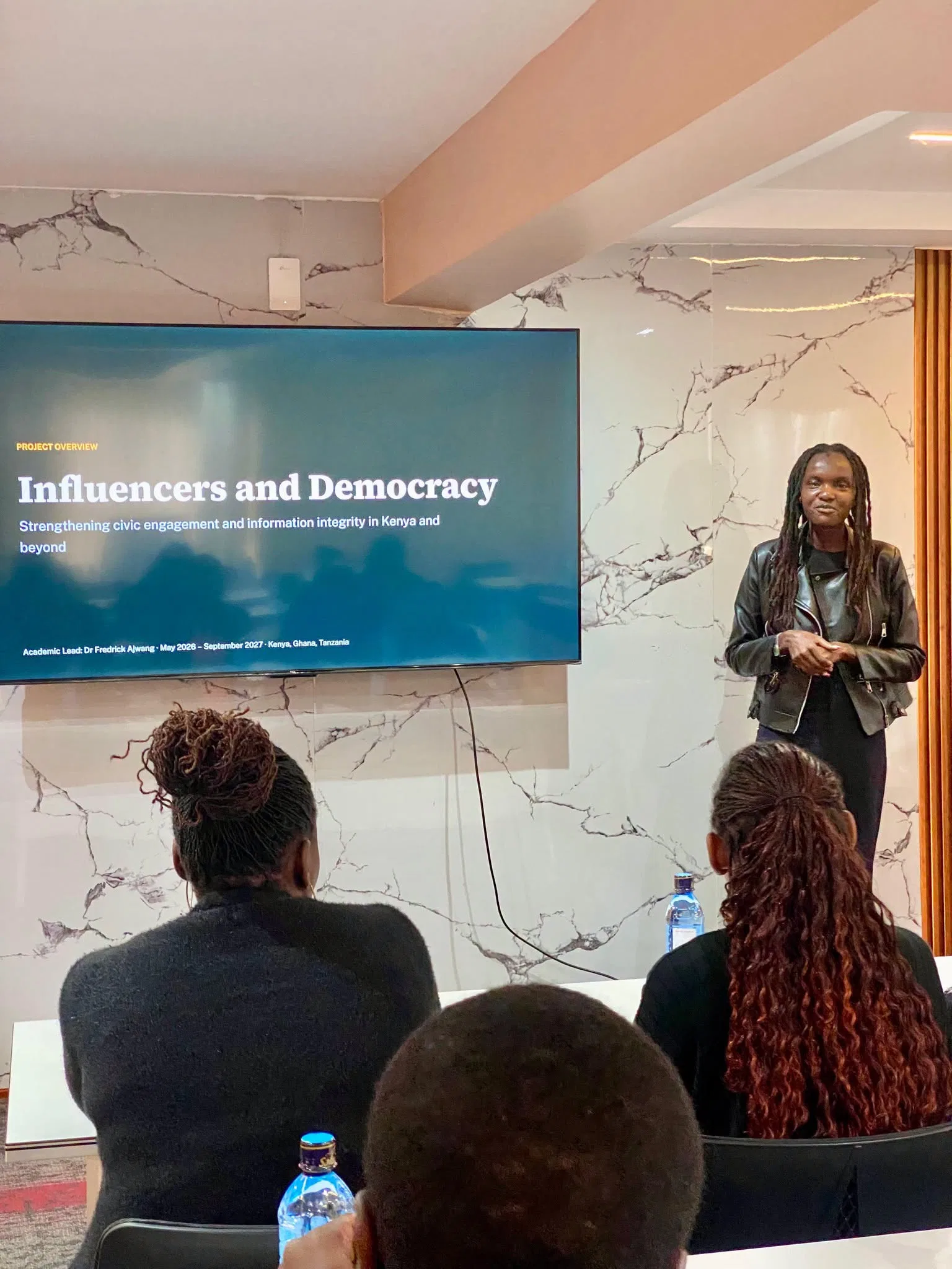 A speaker presents on influencers and democracy at a civic event.